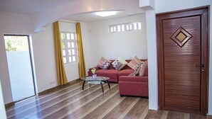 Una sala de estar con un sofá rojo, una mesa de centro de vidrio y una puerta de madera.