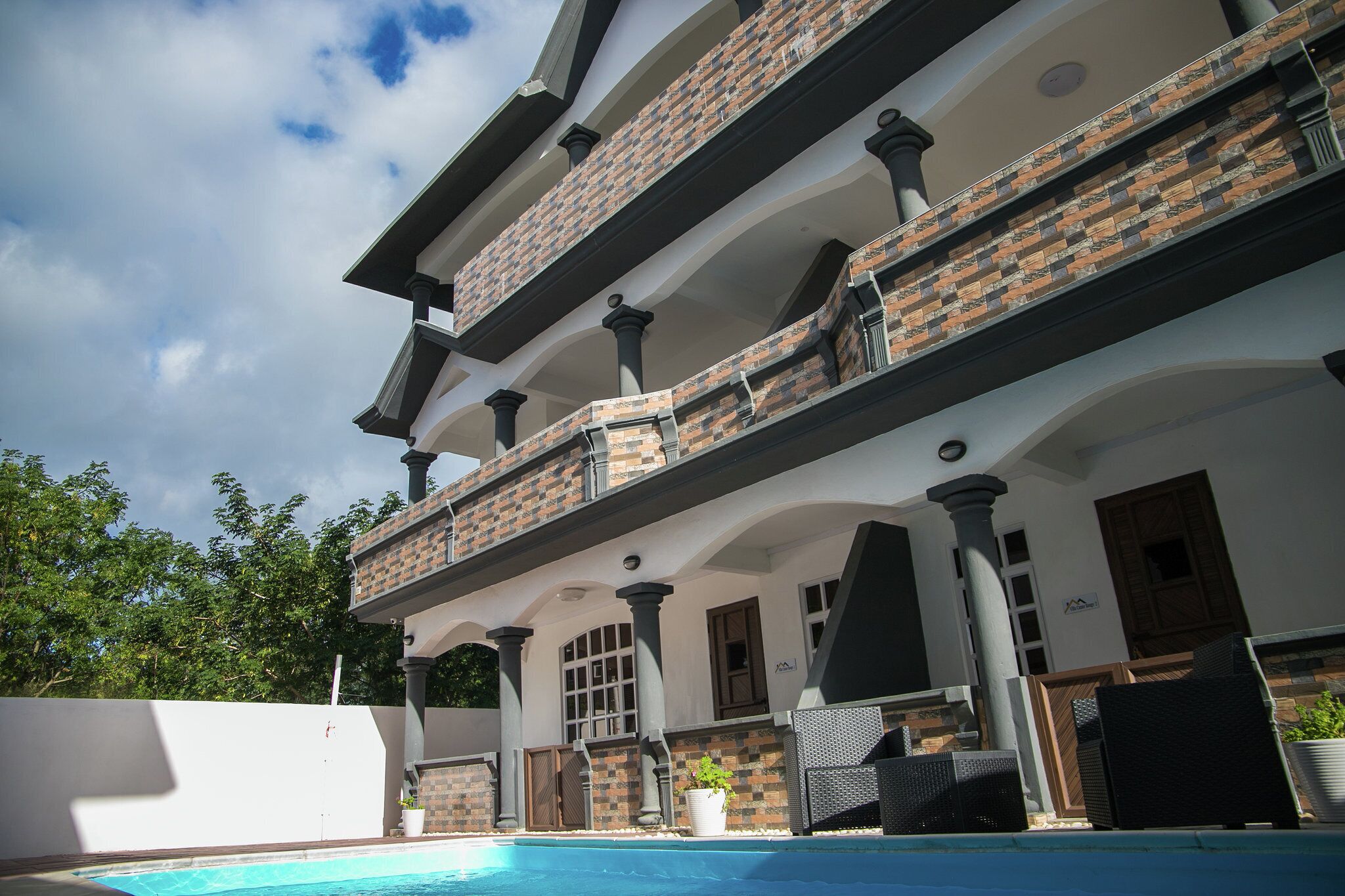 A multi-story building with a swimming pool, outdoor seating, and a brick facade.