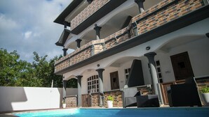 Un edificio de varios pisos con piscina, mobiliario exterior y fachada de ladrillo.