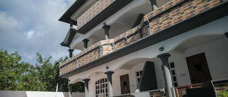 A multi-story building with a swimming pool, outdoor seating, and a brick facade.