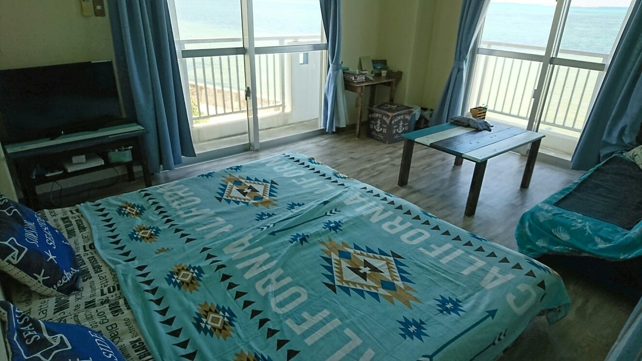 Une chambre avec un lit, une télévision, une table et une vue sur la mer.