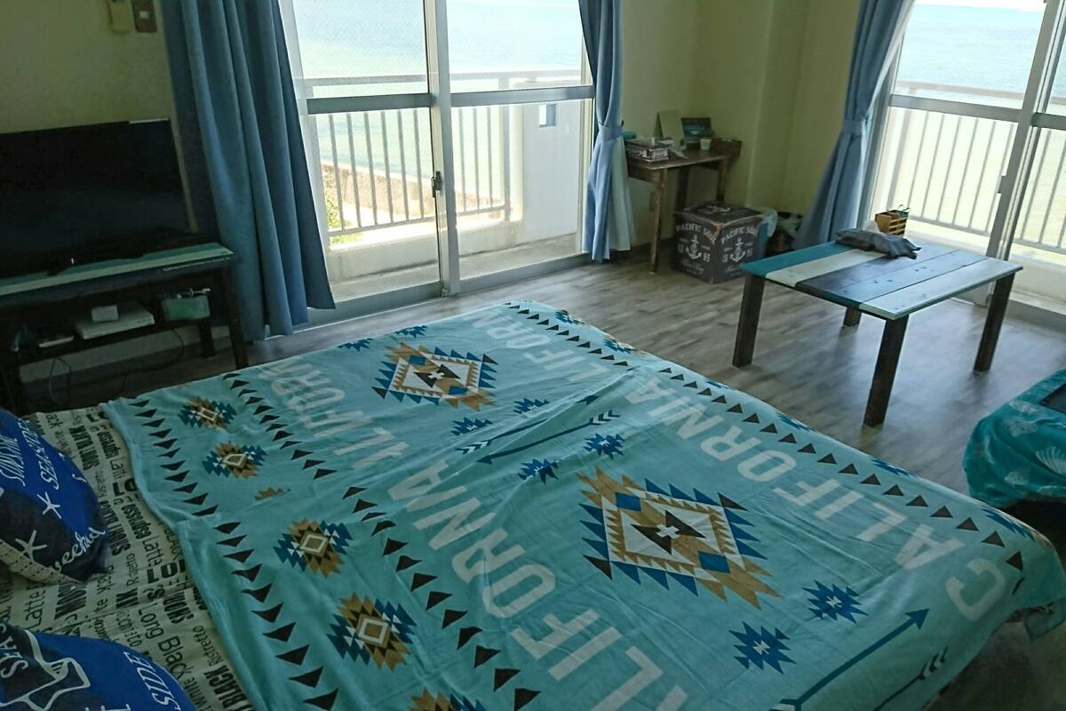 Ein Zimmer mit einem Bett, einem Fernseher, einem Tisch und Meerblick.