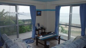 Una habitación con vista al mar, una mesa, dos sofás y un escritorio pequeño con una silla.
