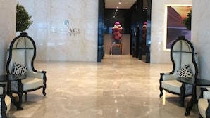A hotel lobby with a marble floor, two ornate chairs with patterned cushions, a reception desk, and a large painting on the wall. - Best Homestay (Kuala Lumpur)