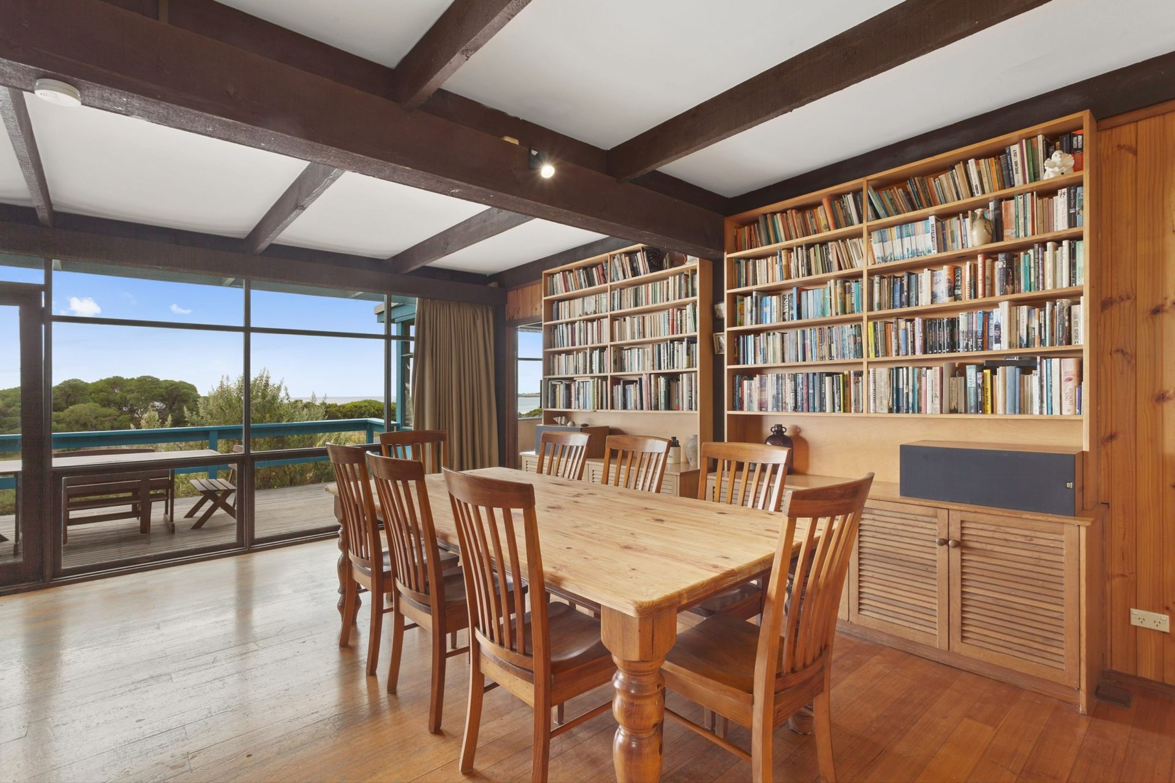 Una habitación amplia con una gran mesa de madera y sillas, rodeada de estanterías llenas de libros.