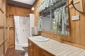 A bathroom with a wooden interior, a white sink, a mirror, and a shower curtain.