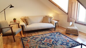 Ein gemütliches Schlafzimmer im Loft-Stil mit hohen Decken, einer Couch, einem Sessel, einem kleinen Tisch und einem dekorativen Korb.