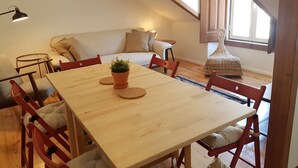 Ein Essbereich mit einem Holztisch, roten Stühlen, einer Topfpflanze und einem kleinen runden Tisch mit einer Lampe.