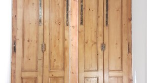 Une porte à deux battants en bois, dotée de charnières métalliques et d’un loquet.