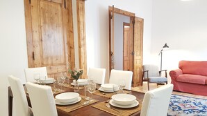 Un espace repas avec une table en bois dressée pour quatre personnes, entourée de chaises blanches.