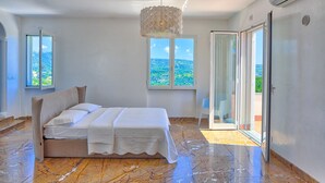 A bedroom with a bed, a chandelier, a view of the outdoors, and a sliding glass door. - Villa Emanuele Costarainera: wonderful modern villa, for 16 ppl, with garden, heated pool, hot-tub (Costarainera)