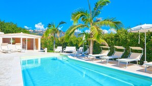 A clear blue pool with white lounge chairs and palm trees. - Villa Emanuele Costarainera: wonderful modern villa, for 16 ppl, with garden, heated pool, hot-tub (Costarainera)