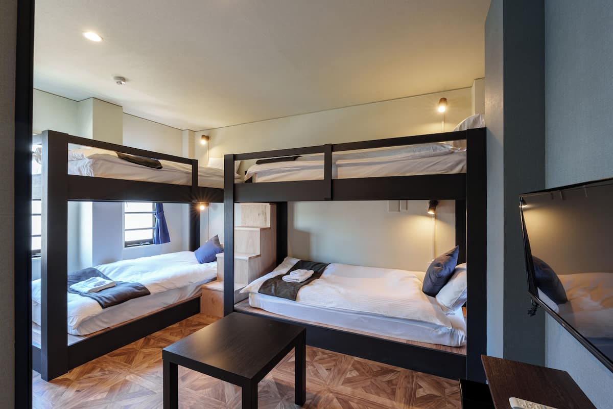 A room with bunk beds, a small table, and a TV.