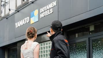 A building with a sign for 'YAMATO DOYANEN HOTELS' and a person pointing at it.