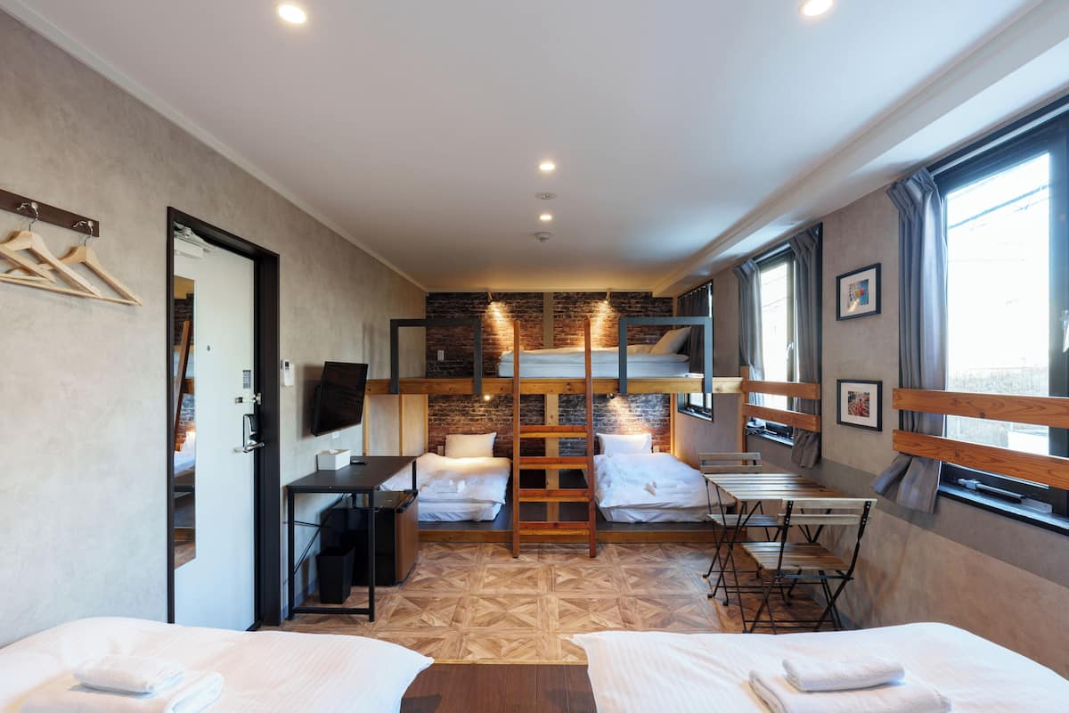 A compact hotel room with bunk beds, a desk, a chair, and a TV.