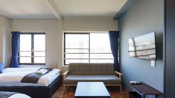 A modern hotel room with a bed, sofa, and a small table.