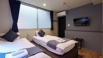 A hotel room with two beds, a TV, and an air conditioning unit.