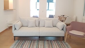 A modern living room with a white sofa, a patterned rug, and a pink chair. - Central and Modern Apartment in a Restored Chalet (Sintra)