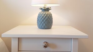 A white bedside table with a pineapple-shaped lamp and a single drawer. - Central and Modern Apartment in a Restored Chalet (Sintra)