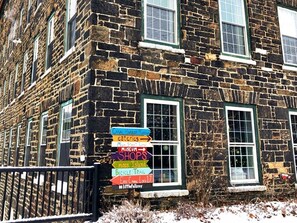 A stone building with a sign indicating nearby attractions such as a museum, shops, and a bicycle trail.