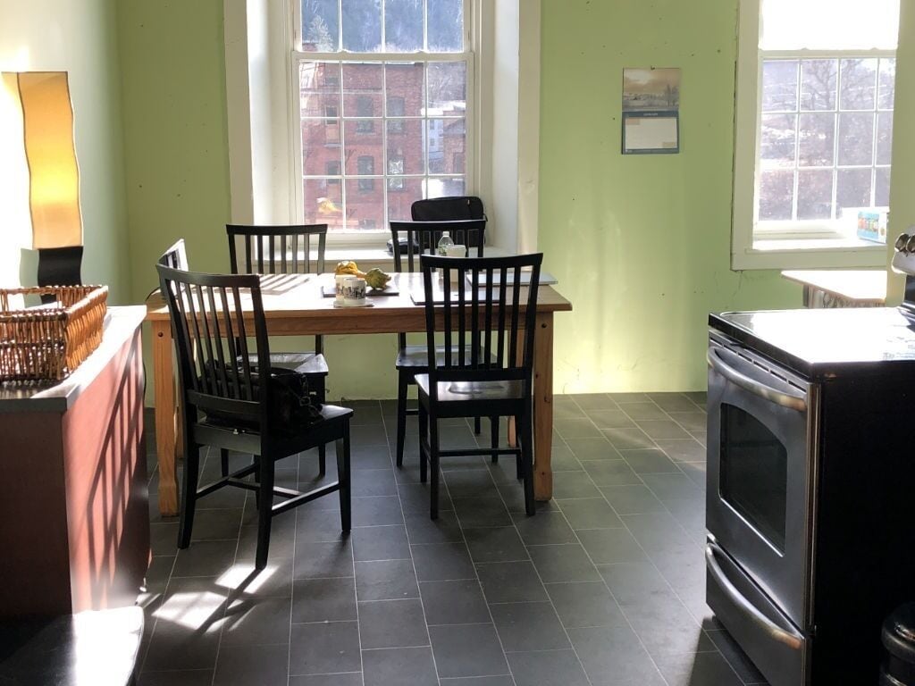 A dining area with a table and chairs, a stove, and a window with a view of buildings.