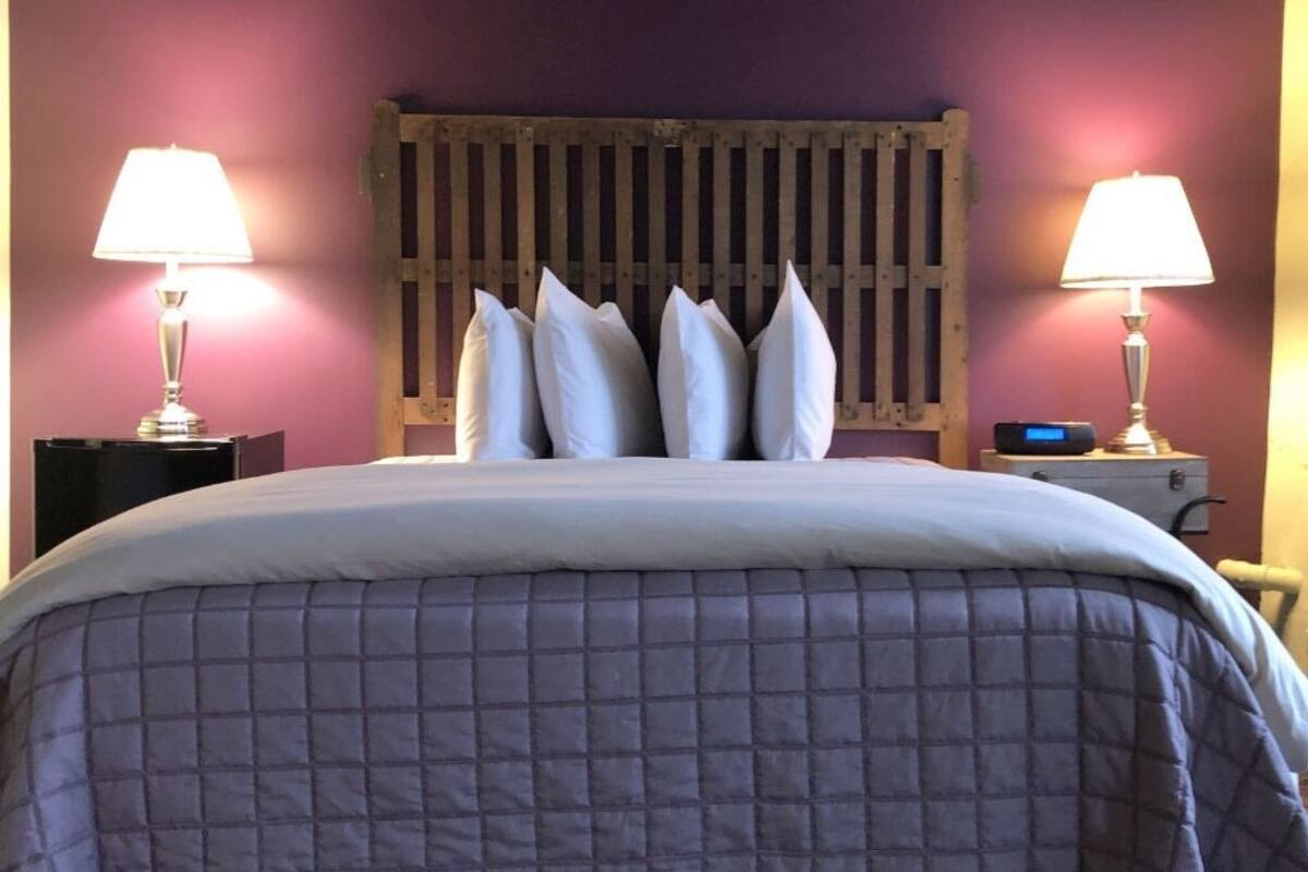 A bed with a quilted cover, a wooden headboard, and two bedside lamps.