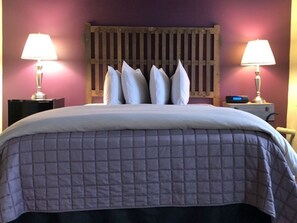 A bed with a quilted cover, a wooden headboard, and two bedside lamps.