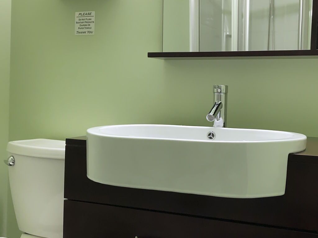 A bathroom with a white sink, a black cabinet, and a white toilet.