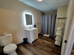 A bathroom with a toilet, sink, mirror, shower curtain, and a towel rack.
