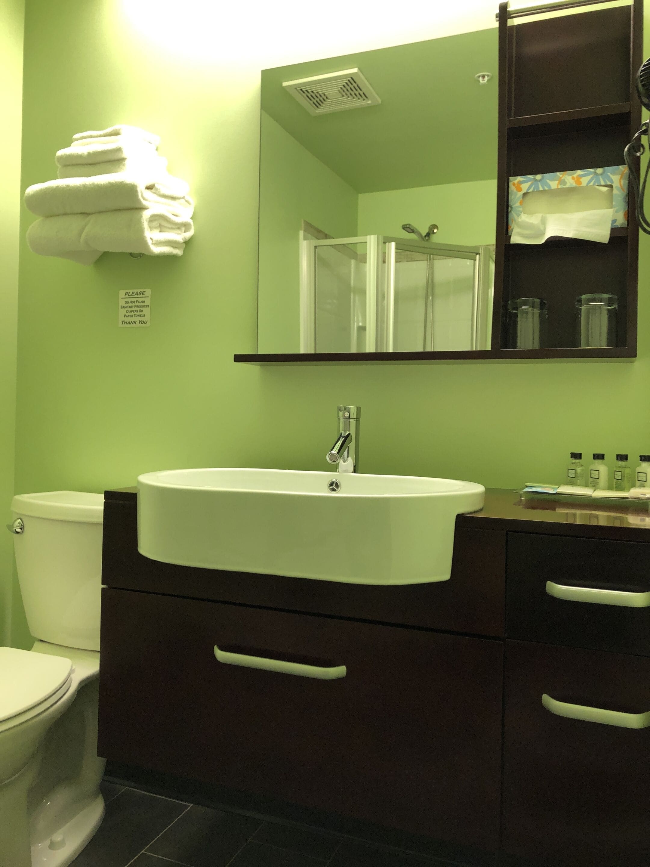 A bathroom with a white sink, dark brown cabinets, a mirror, and a towel rack.