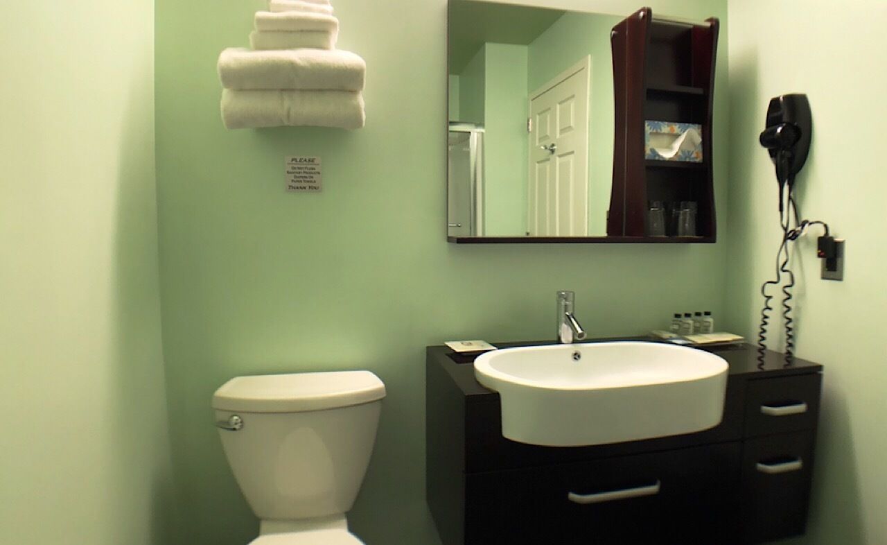 A bathroom with a toilet, sink, and a hairdryer on the wall.