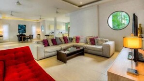 Una sala de estar moderna con un sofá modular, un sillón rojo, una mesa de centro y una lámpara.