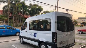 A white van parked on a street with a blue car and a red car in the background.