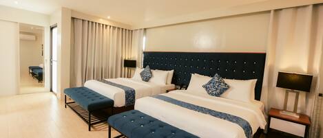 A hotel room with two beds, a bench, a nightstand, and a mirror.