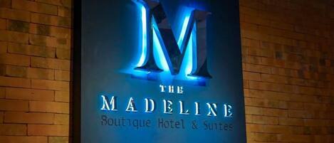 A sign for 'The Madeline Boutique Hotel & Suites' with a prominent 'M' logo.