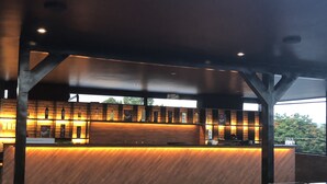 Eine moderne Bar mit Holztresen und Regalen, in denen Flaschen präsentiert werden.