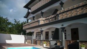 Una casa de dos pisos con piscina, mobiliario de exterior y fachada de ladrillo.