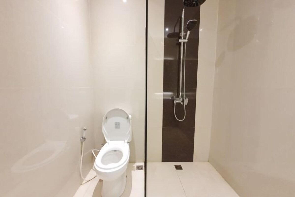 A modern bathroom with a toilet, a glass-enclosed shower, and a small sink.