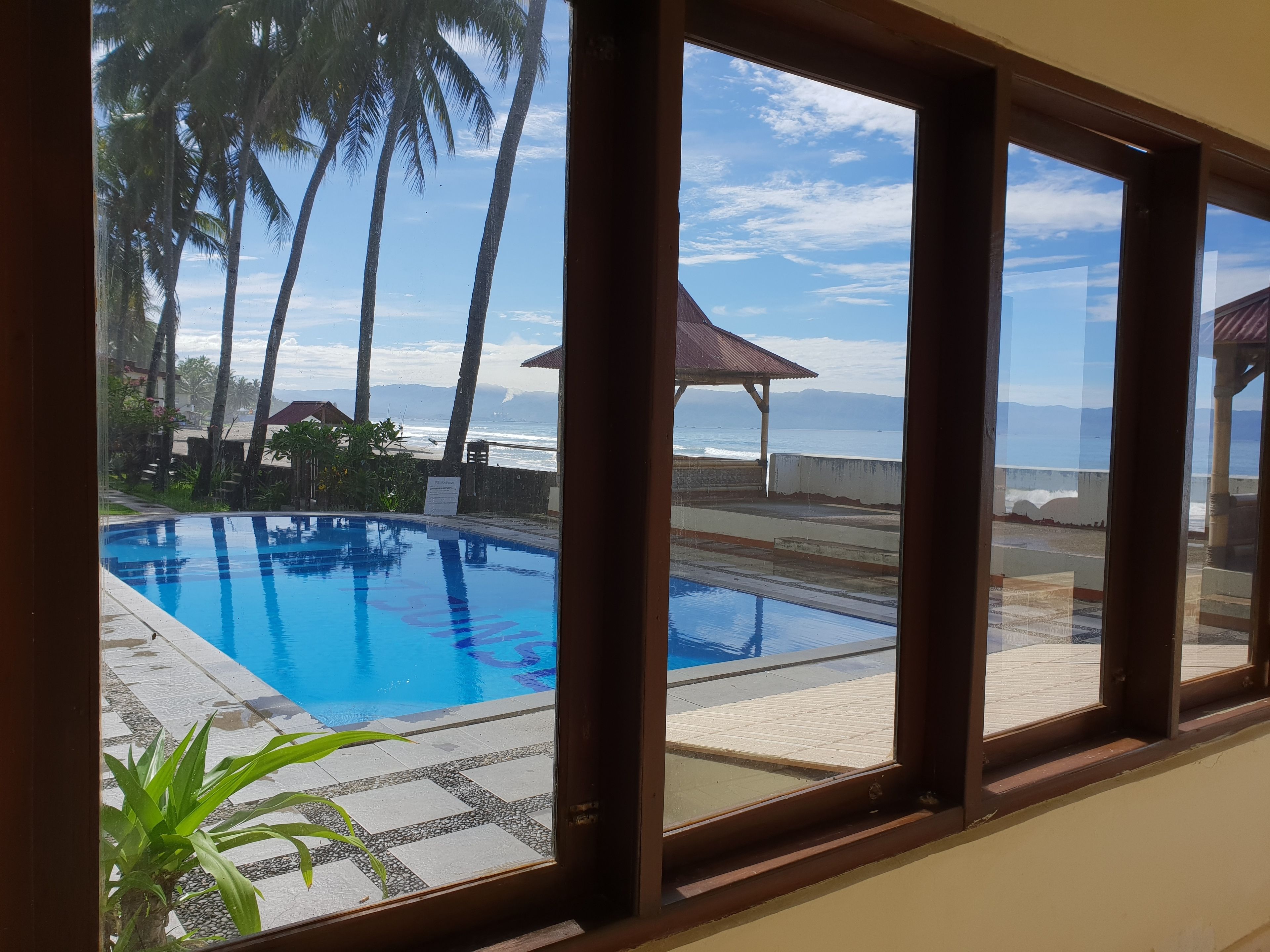 Una piscina con vistas a la playa y palmeras.