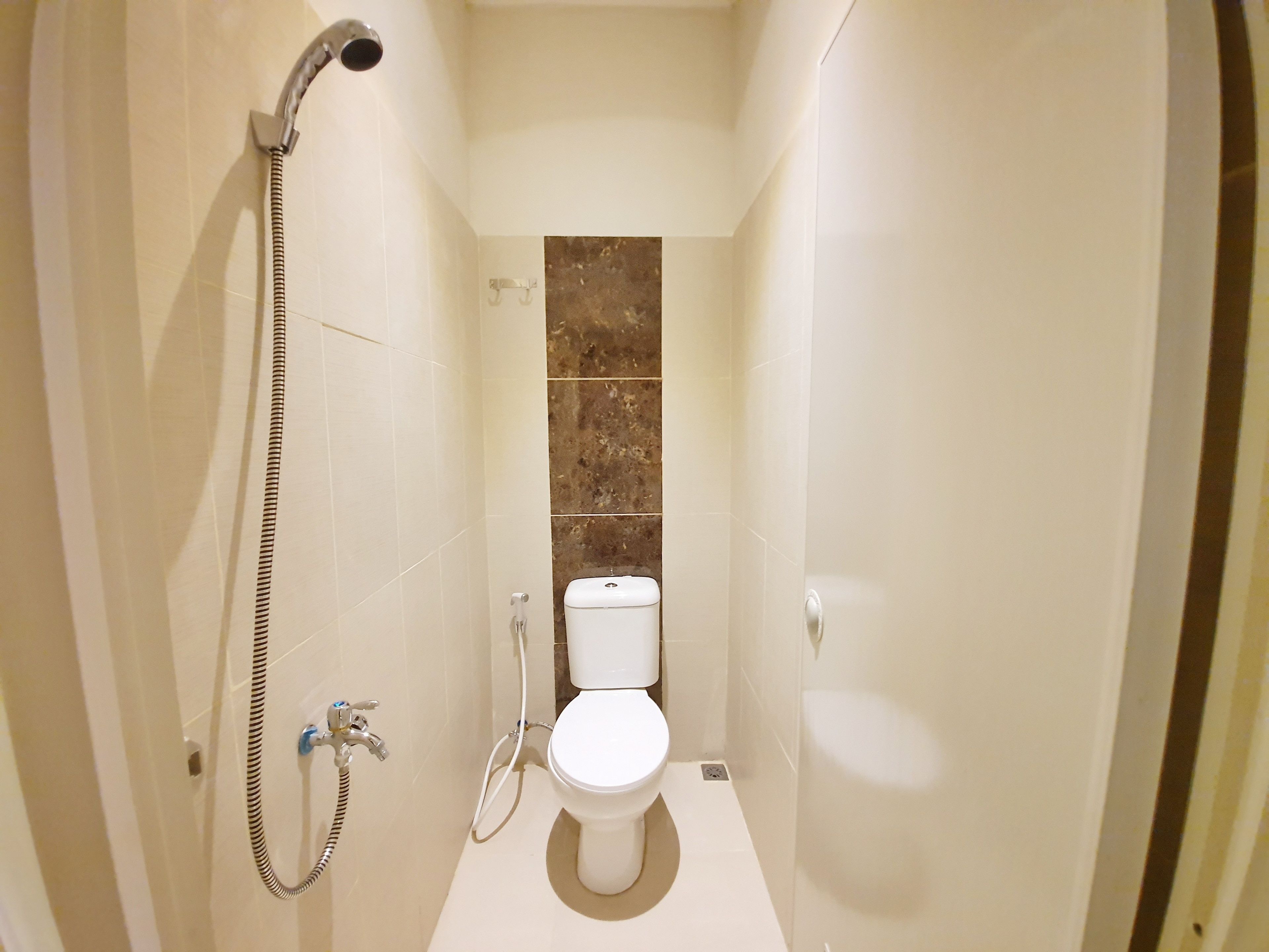 Un baño pequeño y estrecho con inodoro, cabezal de ducha y barra para toallas.