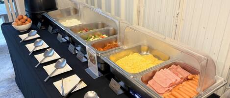 Buffet com diversos alimentos, incluindo ovos, legumes e carnes.