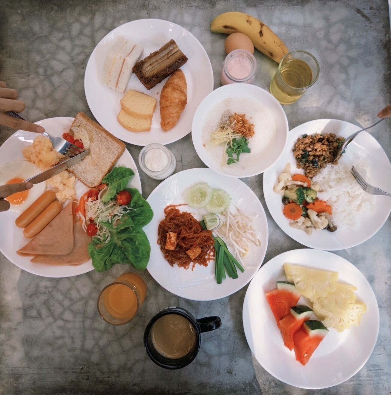Una mesa con varios platos, entre ellos sándwiches, arroz, verduras y un plátano.