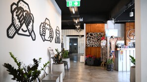 Een gang met plantenpotten, een kledingrek en een fiets.
