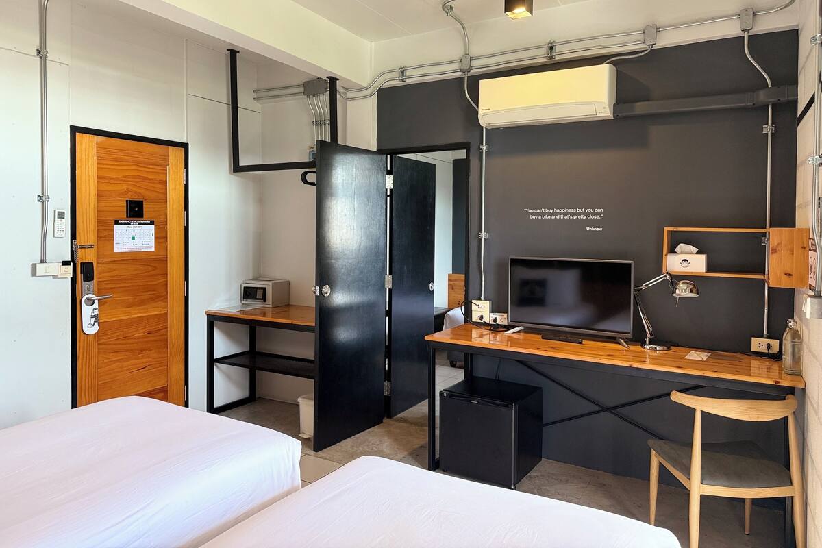 A compact hotel room with a bed, desk, and a TV.