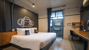Een moderne hotelkamer met een groot bed, een bureau en een badkamer zichtbaar door een geopende deur.