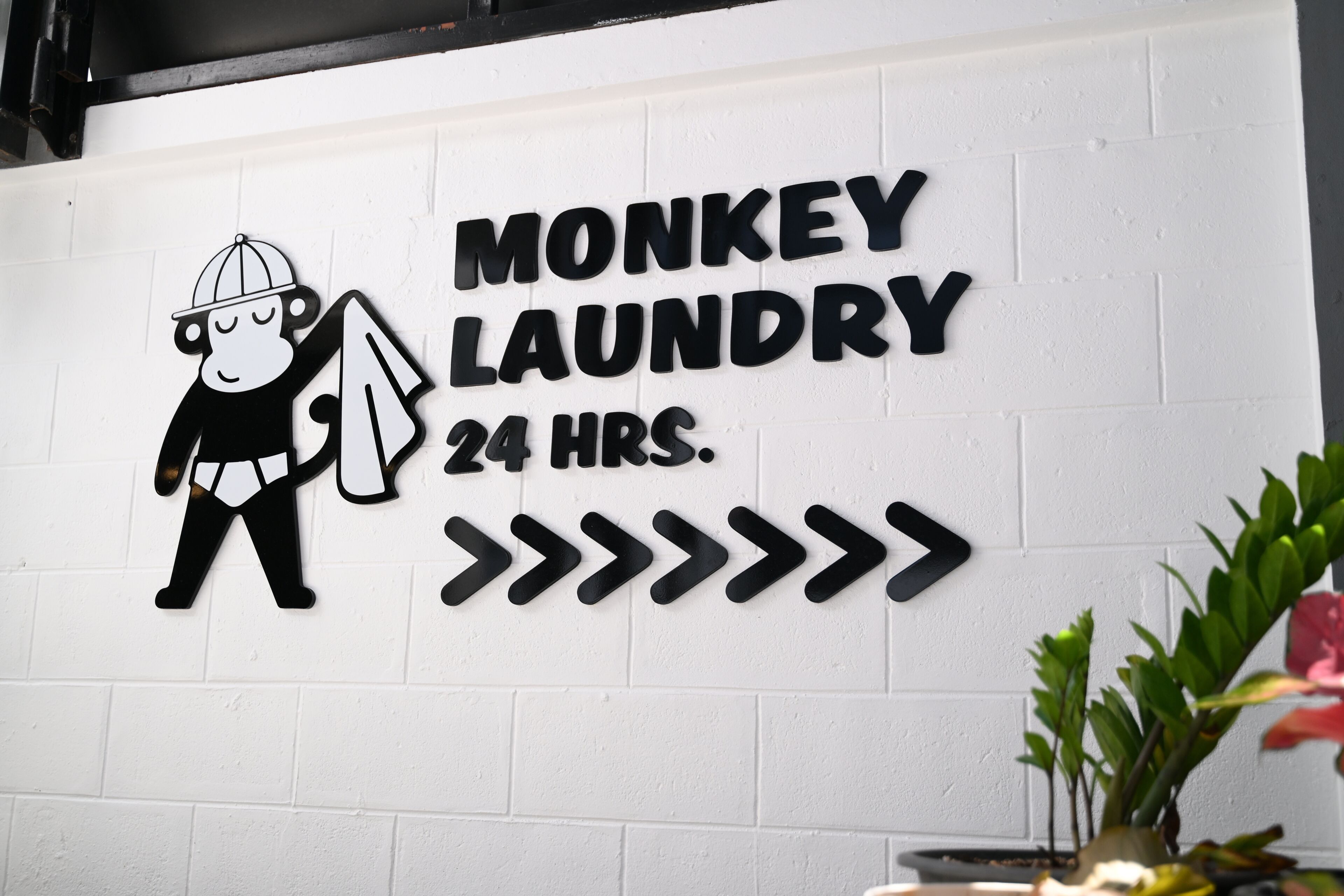 Een bord aan de muur voor 'Monkey Laundry' met een vermelding van 24-uurs service.