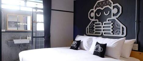 Una habitación de hotel moderna con una cama grande, una obra de arte colgada en la pared y una ventana con vista a la ciudad.