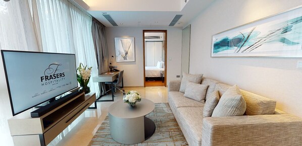Quarto de hotel moderno com televisão de tela plana, sofá, mesa de centro e cama.