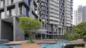 A modern building with multiple balconies and a swimming pool area with wooden decks and surrounding greenery. - Fraser Residence Orchard, Singapore (Singapore)