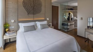 A modern hotel room with a large bed, a wooden accent wall, a closet with glass doors, and a desk with a mirror. - Fraser Residence Orchard, Singapore (Singapore)